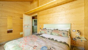 Un dormitorio de cabaña de madera con una cama, una mesita de noche y una pequeña mesa con lámpara.