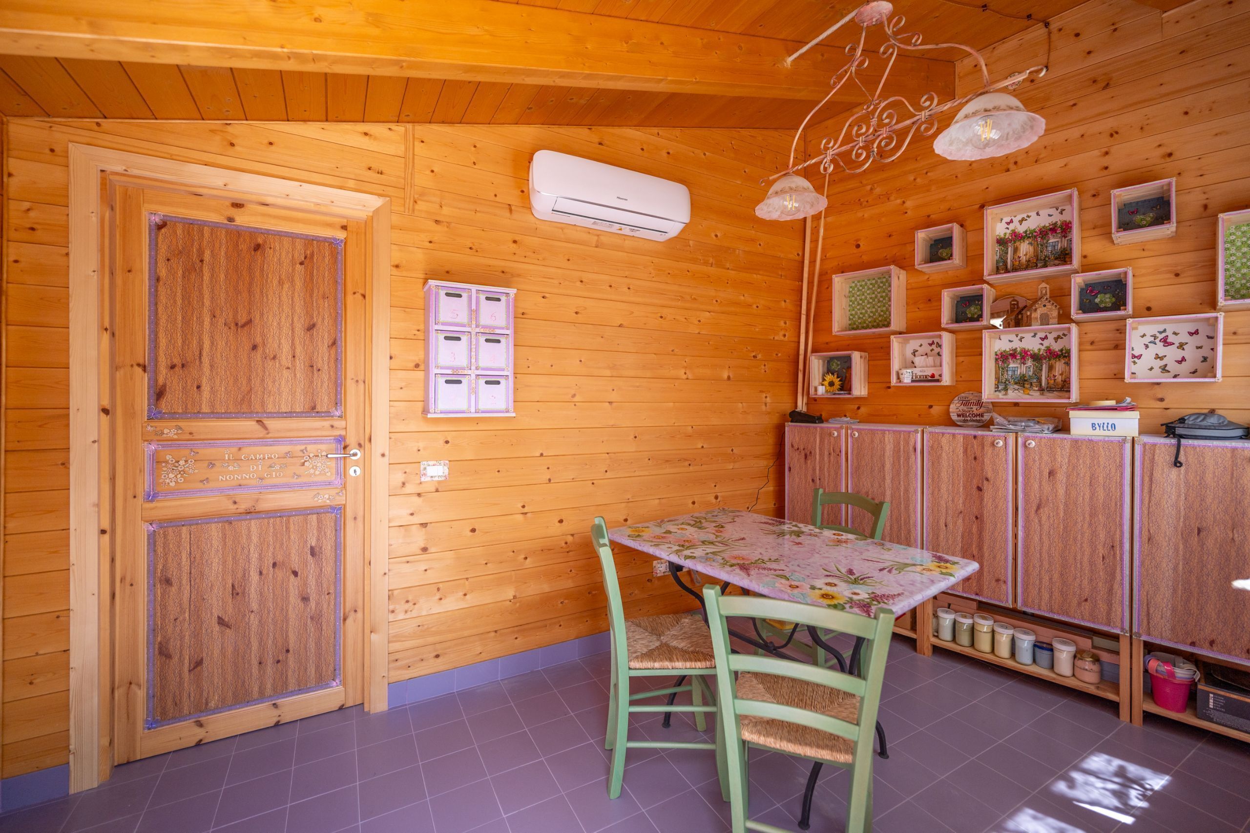 A wooden-paneled room with a table and chairs, an air conditioning unit, and decorative items on the walls.