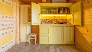 A compact kitchen with yellow cabinets, a tiled backsplash, and a small wooden stool. - Wooden house with porch and garden (Spoleto)