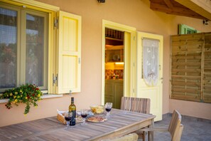 A wooden table with wine glasses and a bottle, set against a yellow wall with a window and a door. - Wooden house with porch and garden (Spoleto)