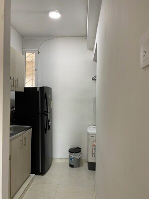 A compact kitchen with a refrigerator, sink, and a trash bin. - Apartaestudio Para Familia de 3-4 Personas y Mascota! A 10 Minutos de la Playa! (Riohacha)