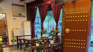 A restaurant interior with wooden furniture, potted plants, and a decorative door. - zhuiyikezhan (Zhangjiajie)