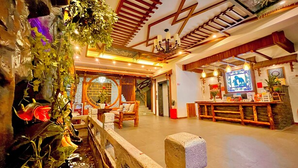 A traditional interior with wooden furniture, a reception desk, and a decorative wall with a circular window. - zhuiyikezhan (Zhangjiajie)