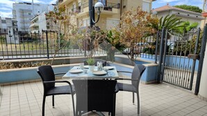 A patio with a table set for four, surrounded by black wicker chairs, and a small tree in the center. - Homiday - Felicioni Alba Adriatica, Trilocale al Piano Terra (Alba Adriatica)