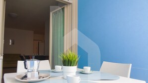 A dining area with a white table set for two, a coffee maker, and a potted plant. - Homiday - Felicioni Alba Adriatica, Monolocale al 1°piano (Alba Adriatica)