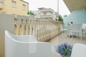 A balcony with white chairs and a table, a decorative railing, and a view of buildings in the background. - Homiday - Felicioni Alba Adriatica, Two-room apartment on the 1st floor (Alba Adriatica)
