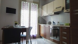 A kitchen with a dining area, a TV mounted on the wall, and a window with curtains. - Homiday - Felicioni Alba Adriatica, Two-room apartment on the 1st floor (Alba Adriatica)