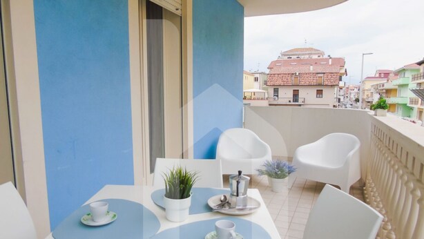 A balcony with a table set for two, white chairs, and potted plants. - Homiday - Felicioni Alba Adriatica, Two-room apartment on the 1st floor (Alba Adriatica)