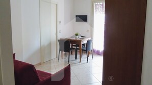 A dining area with a table and chairs, a door, and a window with curtains. - Homiday - Felicioni Alba Adriatica, Two-room apartment on the 1st floor (Alba Adriatica)