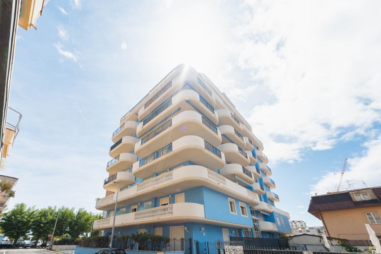 A multi-story building with balconies and a blue facade.