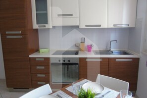 A modern kitchen with wooden cabinets, a built-in oven, and a stainless steel sink. - Homiday - Felicioni Alba Adriatica, Two-Bedroom Apartment on the 1st Floor (Alba Adriatica)