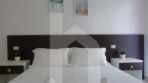 A modern hotel room with a large bed, two bedside tables with plants, and artwork on the walls. - Homiday - Felicioni Alba Adriatica, Two-room apartment (Alba Adriatica)