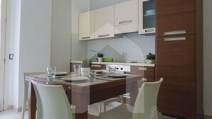 A modern kitchen with white cabinets, a wooden dining table, and chairs. - Homiday - Felicioni Alba Adriatica, Two-room apartment (Alba Adriatica)