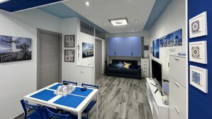 A modern room with a dining area, a sofa, and a TV. - Brand new apartment near the sea (Fuscaldo)