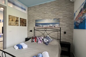 Une chambre à coucher comprenant un lit, des oreillers, une table de chevet et un mur décoré d’œuvres d’art sur le thème de la marine.