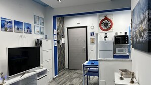 A compact kitchen with a TV, microwave, and refrigerator. - Brand new apartment near the sea (Fuscaldo)