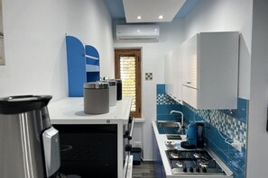 Une cuisine compacte équipée d’une cuisinière à gaz, d’une machine à café et d’un four à micro-ondes.