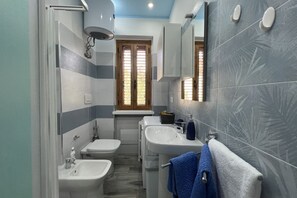 Une salle de bain moderne équipée d’un bidet, de toilettes, d’un lavabo et d’un miroir.