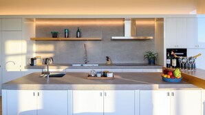 Une cuisine moderne dotée d’un îlot central, d’appareils électroménagers intégrés et d’un design minimaliste.