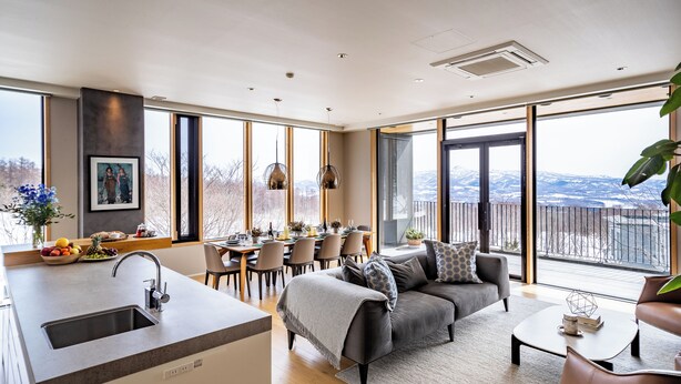 Une cuisine moderne dotée d’un grand îlot central, d’un coin repas avec des chaises, d’un canapé et d’une vue sur les montagnes.