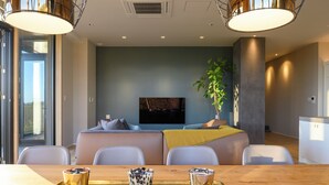 Un salon moderne avec un canapé, une table basse sur laquelle sont posées des boissons et un téléviseur fixé au mur.