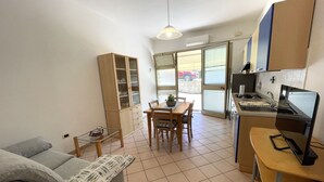 A compact living space with a kitchenette, dining area, and a sofa. - Dante Apartment (Porto Azzurro)