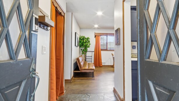A hallway with a bench, a welcome sign, and a plant. - Experience Wichita living near WSU!  Fire Pit, Pool Table, and Arcade games. (Wichita)