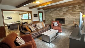 A cozy living room with a stone fireplace, leather sofas, and a pool table. - Experience Wichita living near WSU!  Fire Pit, Pool Table, and Arcade games. (Wichita)