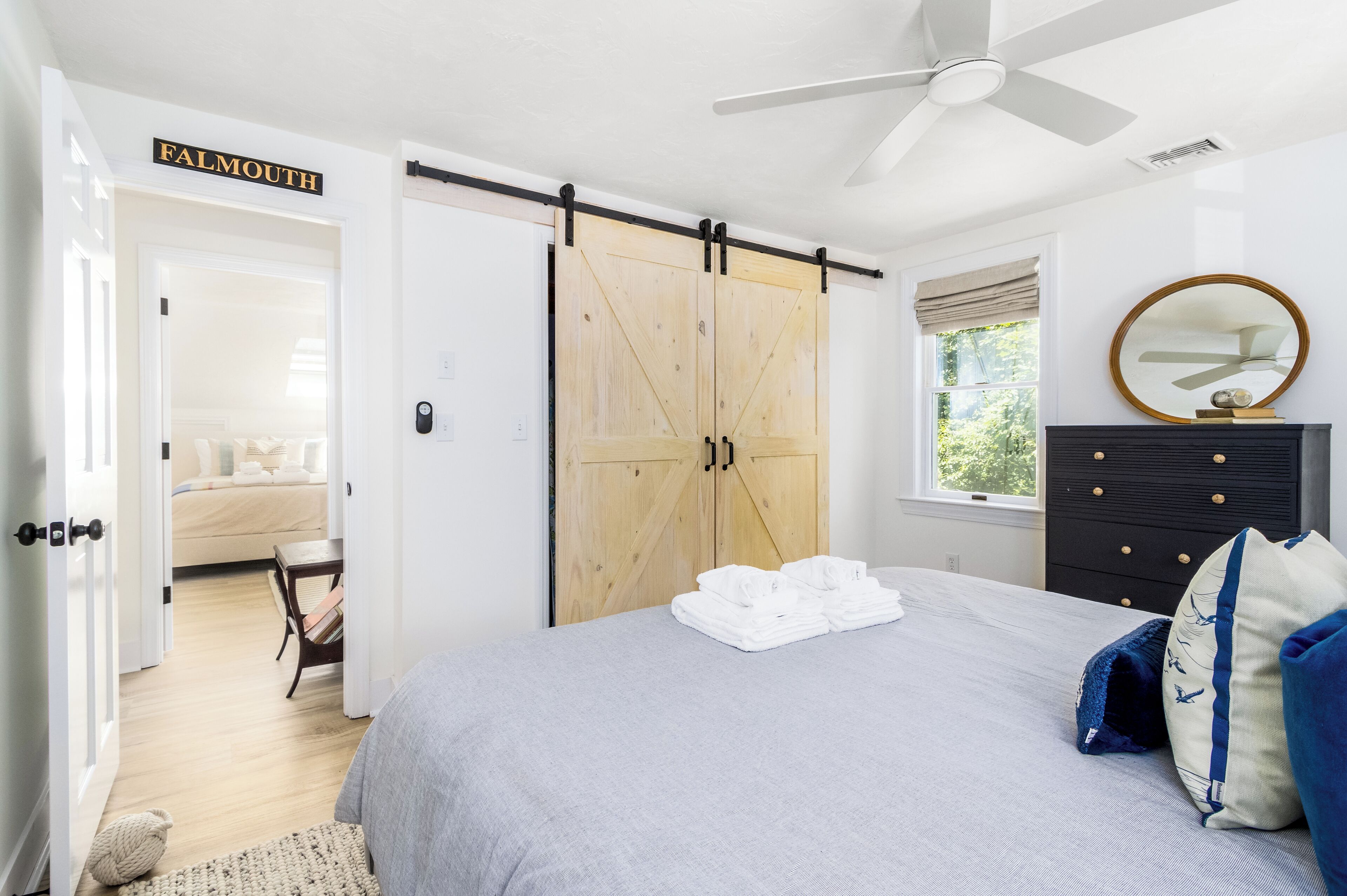 Un dormitorio con cama, puerta corrediza de estilo rústico, cómoda y ventilador de techo.
