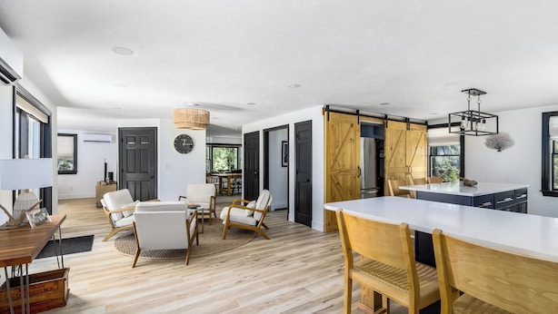 A spacious kitchen with a large island, wooden flooring, and a dining area with chairs and a table.