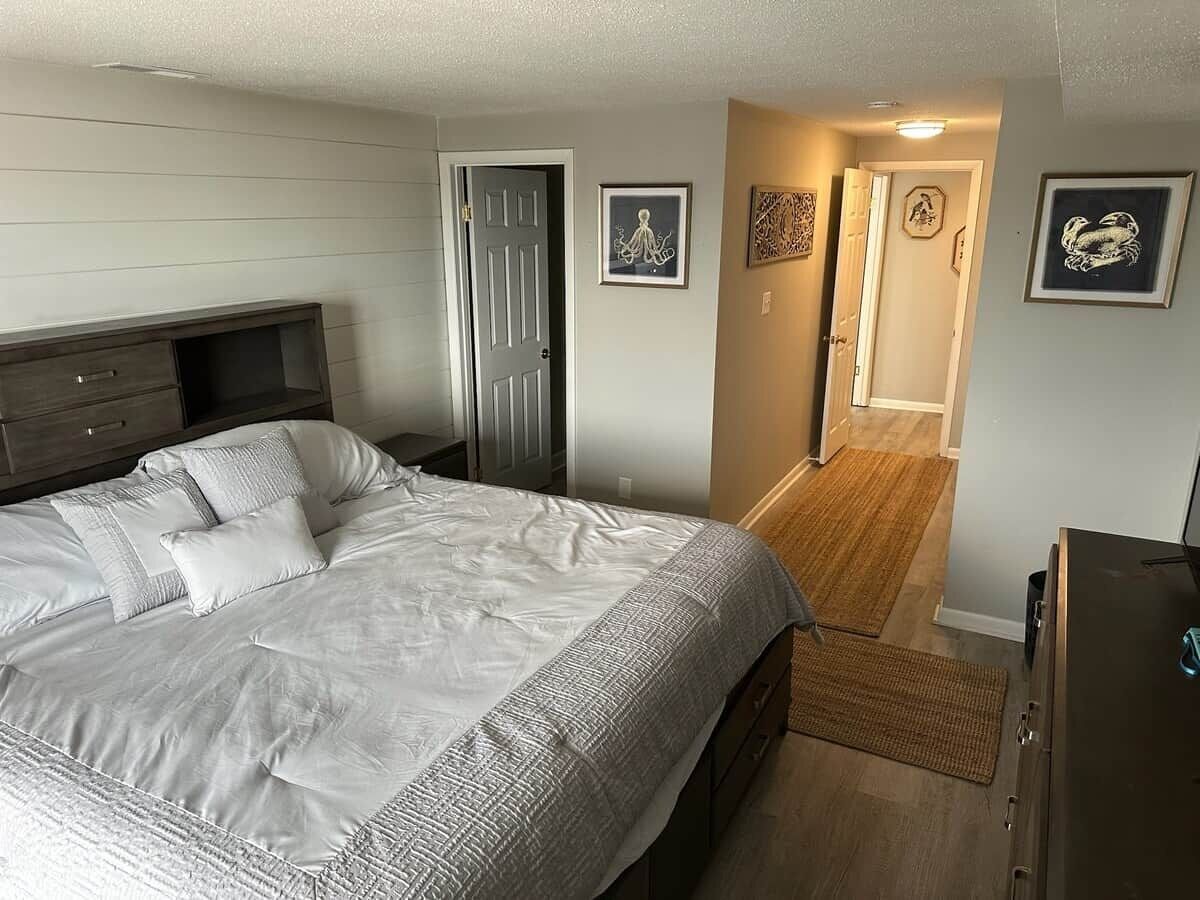 Un dormitorio con una cama grande, un aparador, una puerta y un pasillo que conduce a otra habitación.