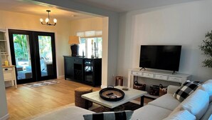 A modern living room with a sofa, television, and a dining area with a table and chairs.