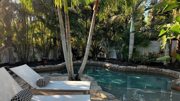 A poolside area with lounge chairs and a small pool, surrounded by tropical plants.