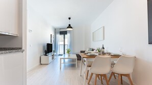 A modern kitchen with a built-in oven, a dining area with a table and chairs, and a large window providing natural light. - MalagaSuite Quintana Holidays (Torremolinos)