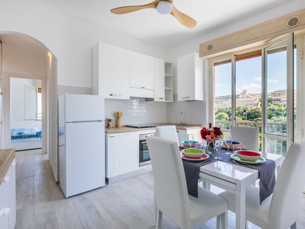 A modern kitchen with white cabinetry, a built-in oven, and a dining area with a table set for two.