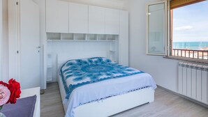 A bedroom with a bed, a ceiling fan, a window with a view of the sea, and a radiator. - Apartment Mauro by Interhome (San Vincenzo)