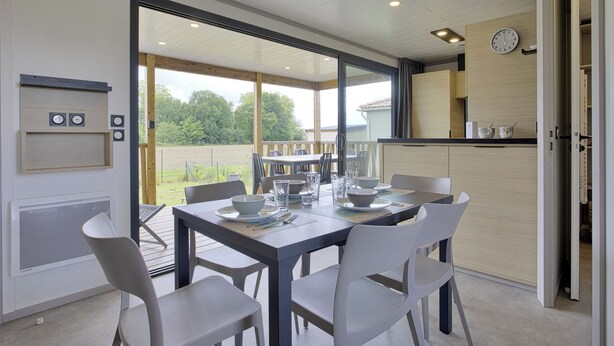 A modern kitchen with a dining area, large windows, and a view of the outdoors.