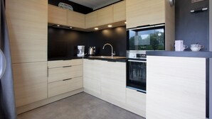 A modern kitchen with light wood cabinets, a black countertop, a Bosch oven, and a WiFi sign.
