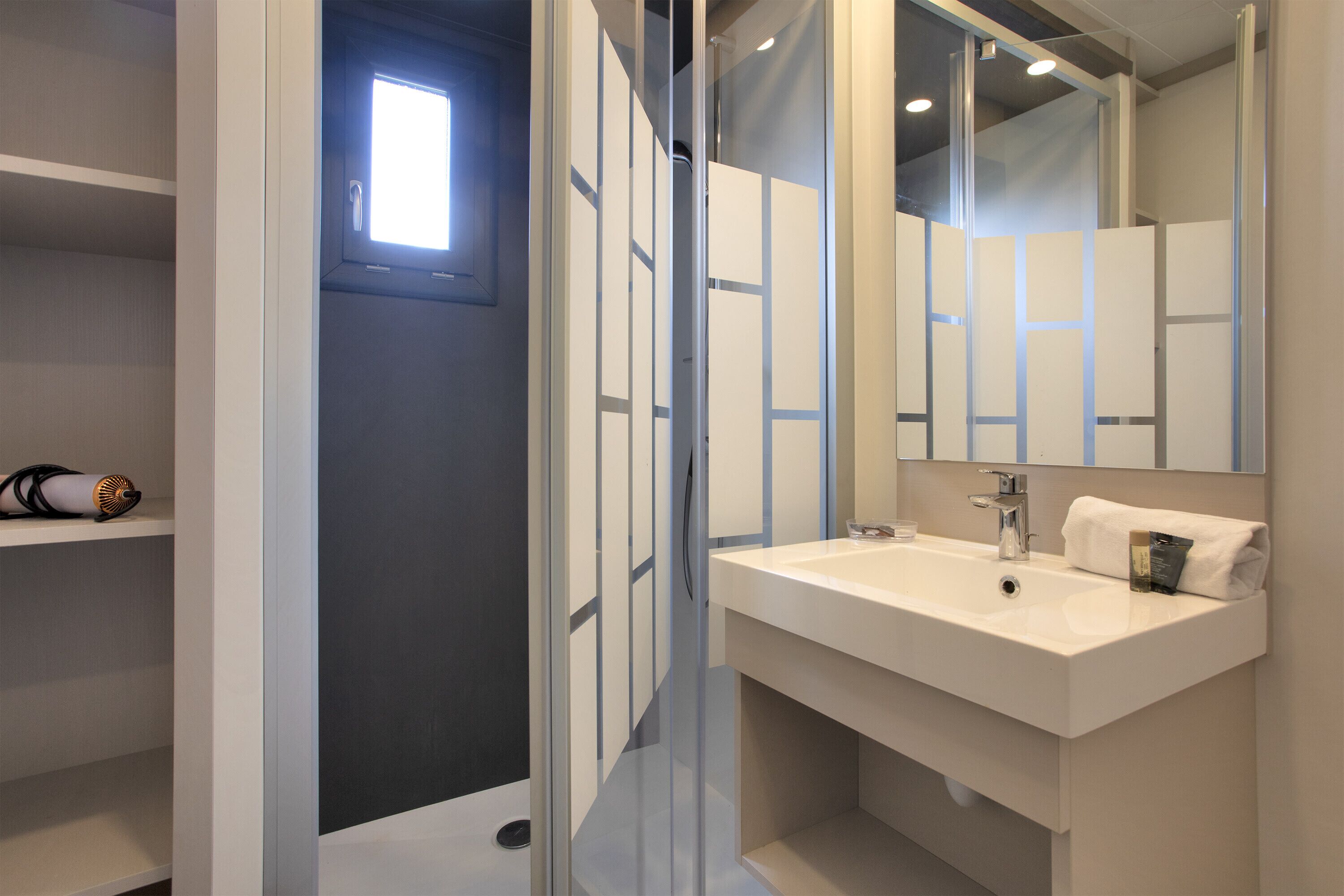 A modern bathroom with a large mirror, a white sink, and a towel.