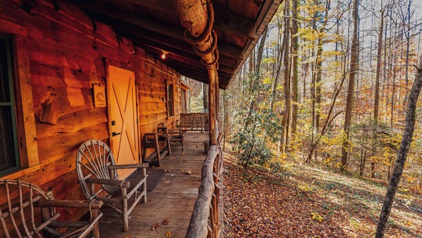 A wooden cabin with a porch, a bench, and a chair. - Saluda Summit at Saluda Grade Cabins! (Saluda)