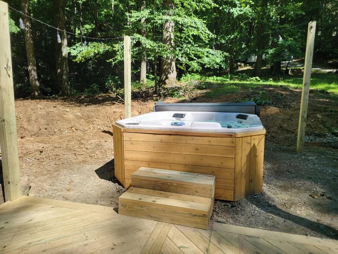 Ein Whirlpool mit hölzernen Stufen, eingebettet in eine natürliche Waldlandschaft.