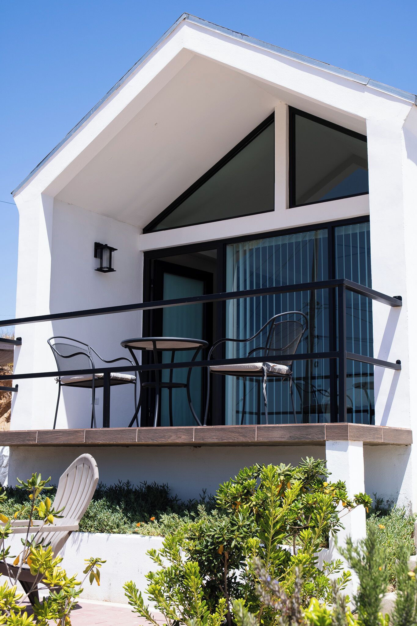 A modern building with a balcony, two chairs, and a table.