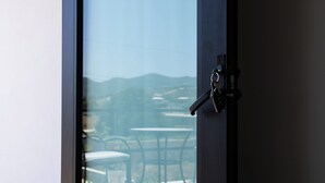 Blick durch ein Fenster mit einem Metallriegel, ein Tisch und Stühle davor.