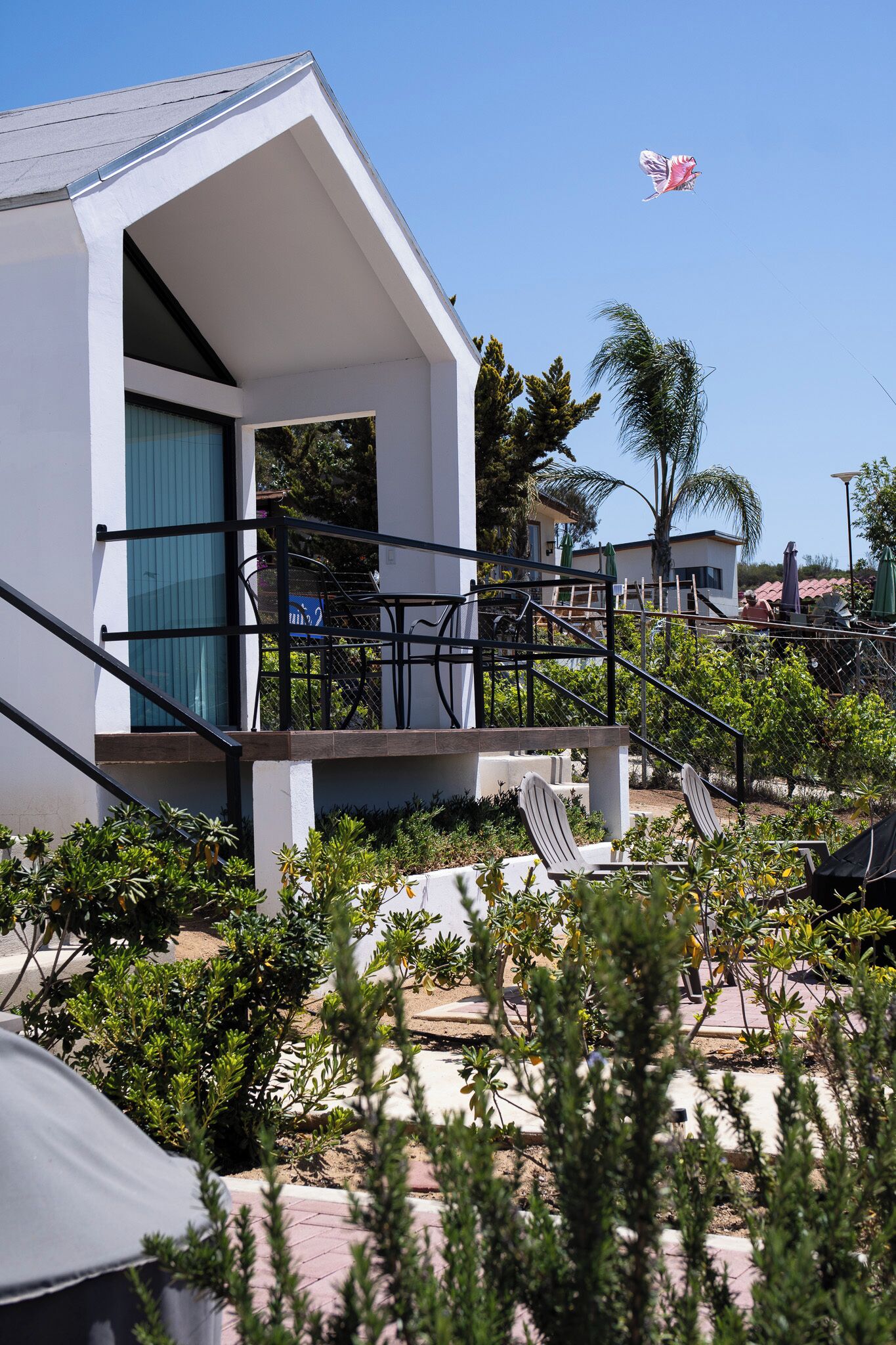 A modern building with a balcony, outdoor seating, and a clear sky.