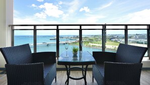 A balcony with a table and two chairs, overlooking a marina and cityscape.