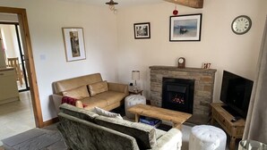 A cozy living room with a fireplace, a sofa, a coffee table, and a television.