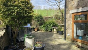 A stone building with a window and a potted plant arrangement.