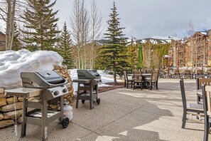En udendørs patio med grill, spiseborde og stole.