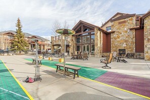 A building with stone walls, a large entrance, outdoor seating, and a green bike lane. - Ski in, ski out resort at Grand Timber Lodge in beautiful Breckenridge, CO (Breckenridge)