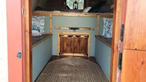 Un couloir étroit et voûté qui mène à une chambre dotée d’un lit superposé et d’une petite fenêtre.